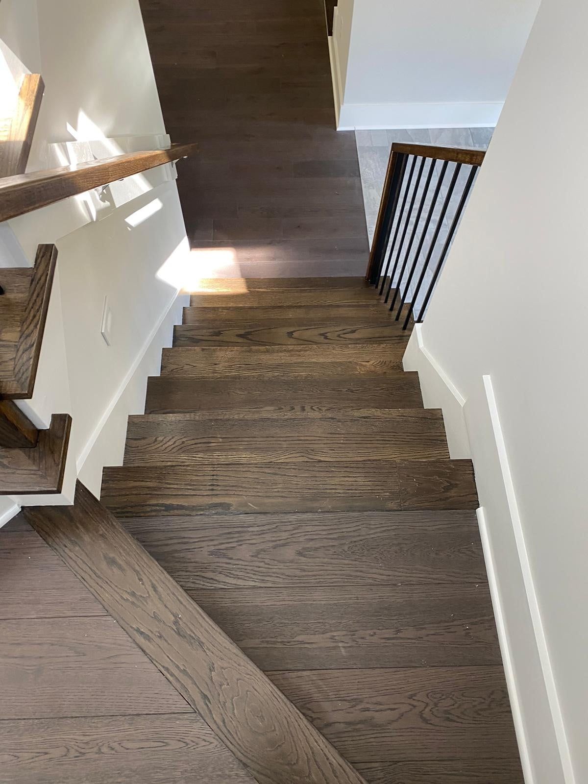 Wooden staircase with dark treads and a black metal railing.