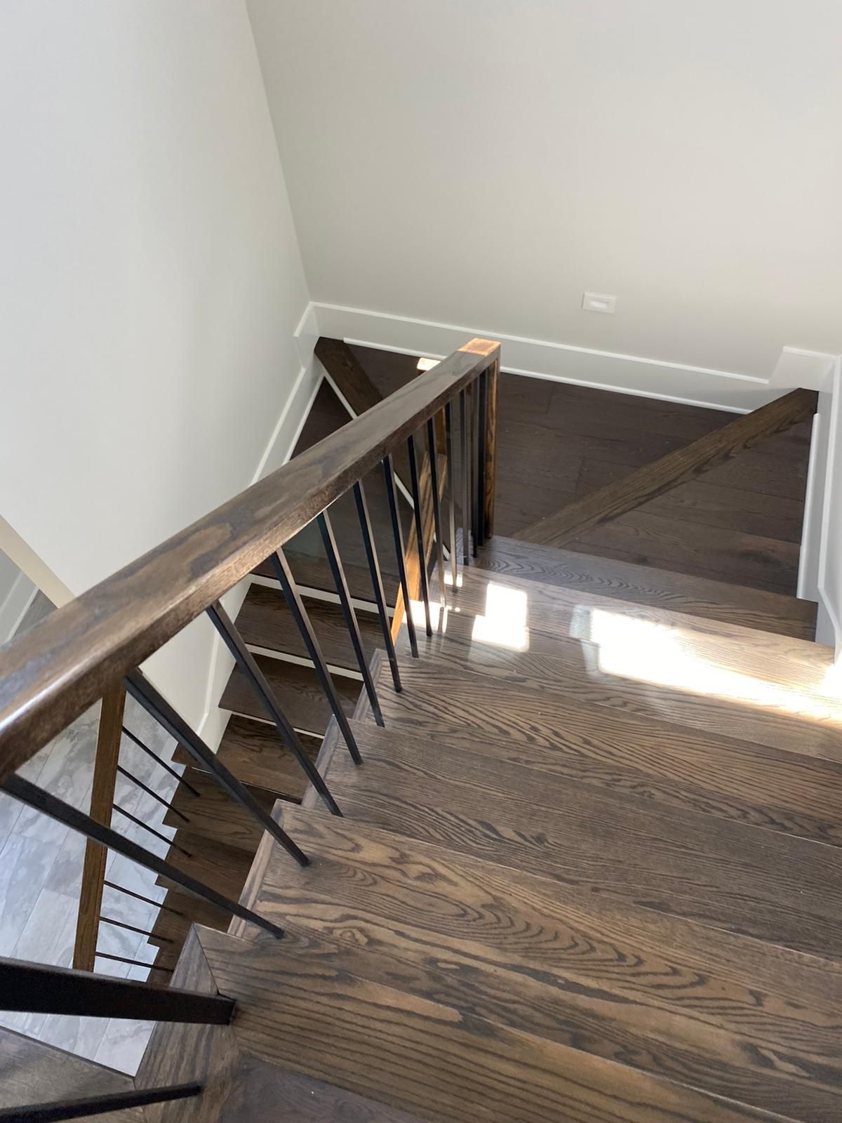 Wooden staircase with dark stained treads and a dark banister with black metal spindles.
