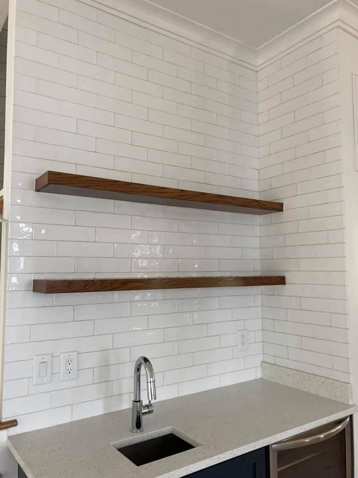 Two wood shelves on a white tiled wall above a countertop with a sink; a cabinet with a wine cooler is below.