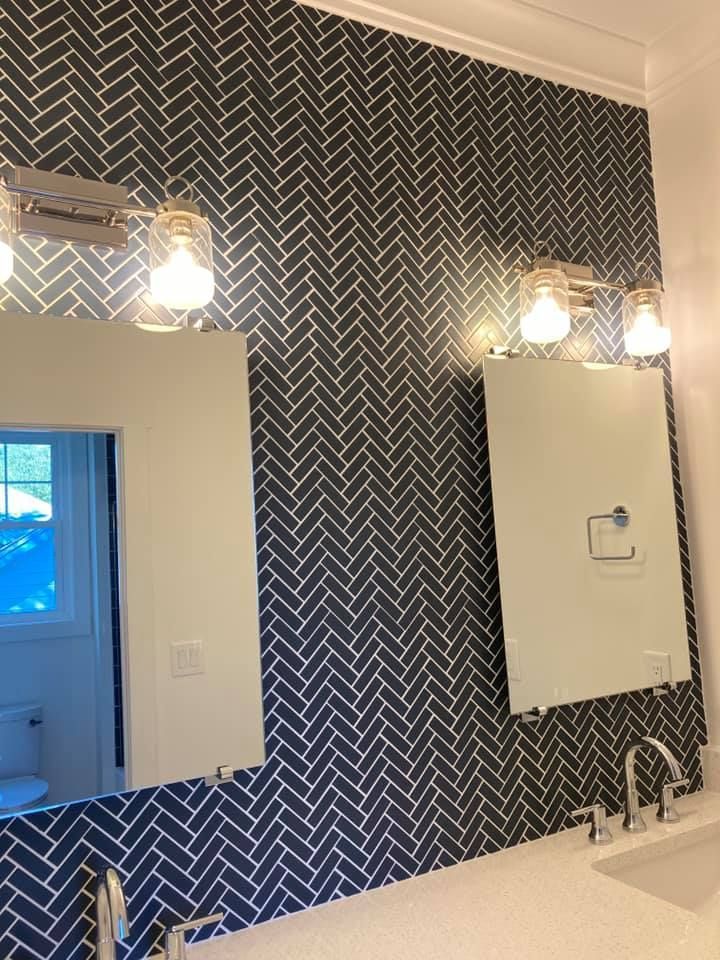 Bathroom with navy blue herringbone tile wall, mirrors, and brushed nickel fixtures.