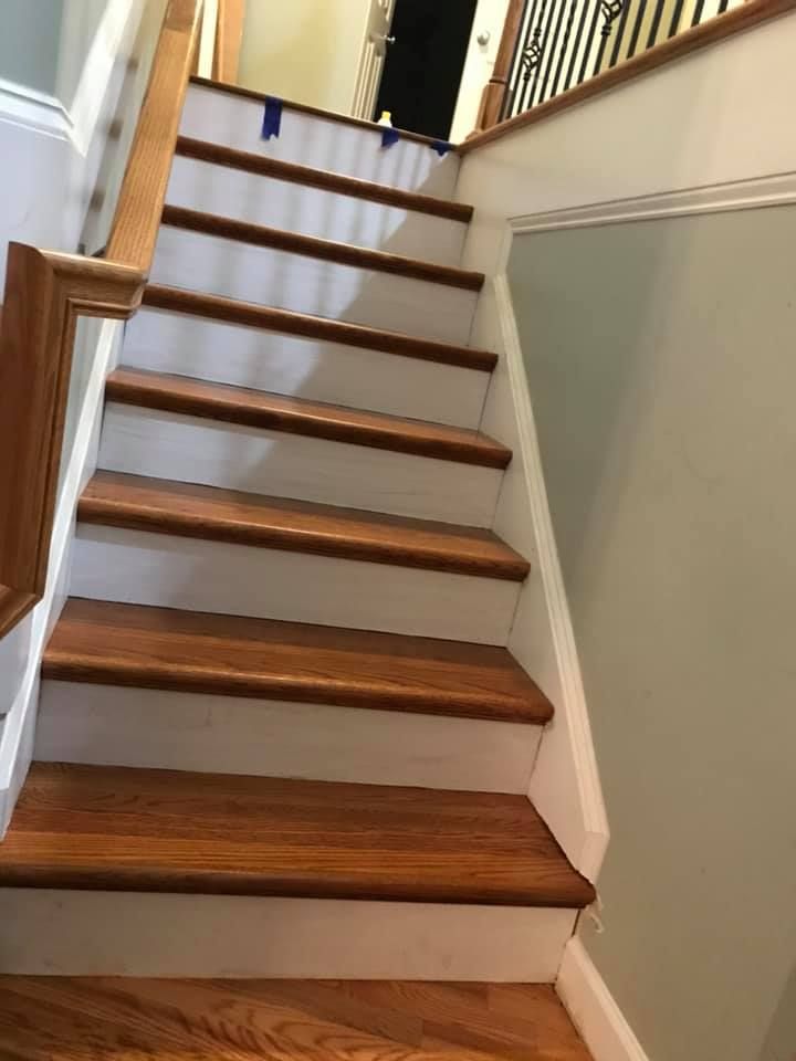 Wooden staircase with brown treads, white risers, and a light-colored wall on the side.