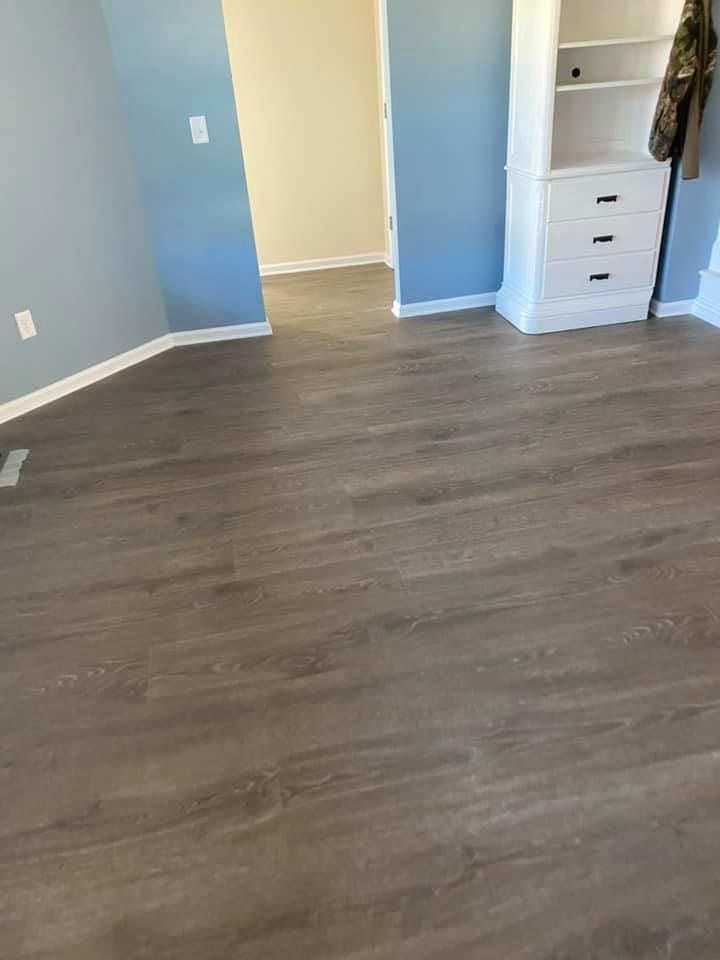 Room with gray wood-look flooring, light blue walls, and a white built-in cabinet with drawers.
