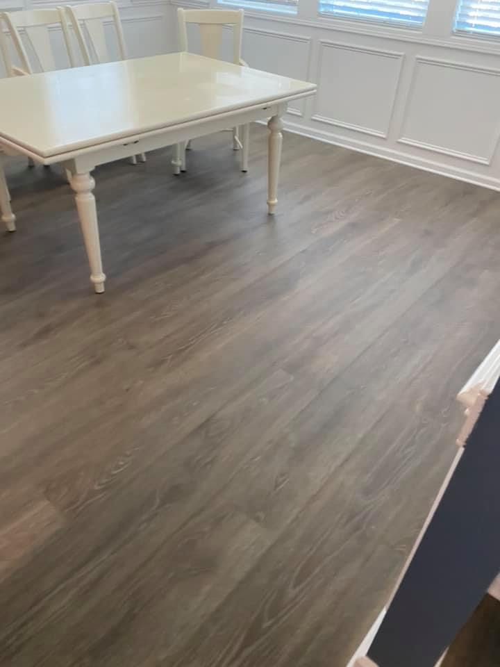Dining room with a white table and chairs on a wooden floor; white paneled walls.