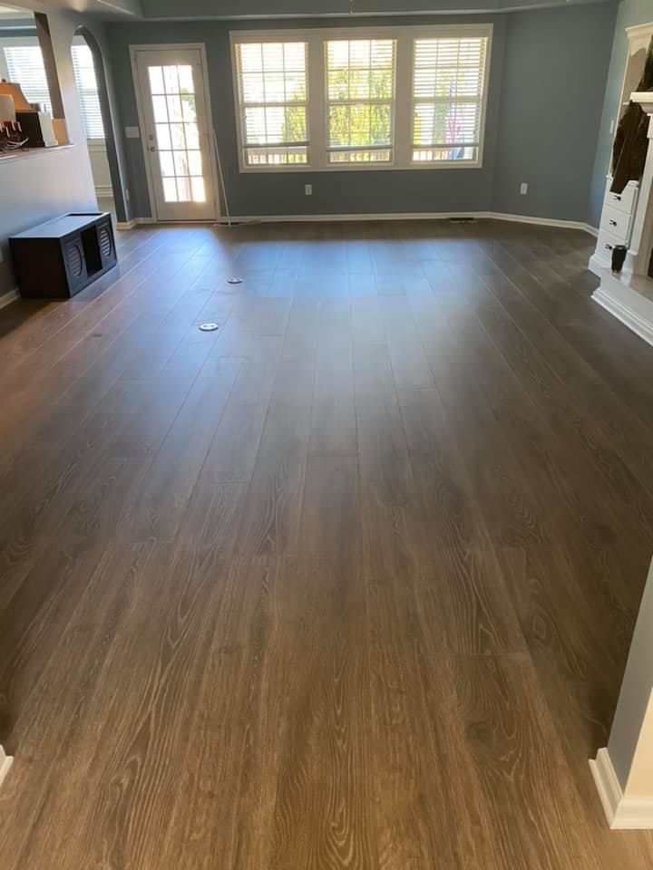 Hardwood floors in a bright living room, with a door and windows allowing natural light.