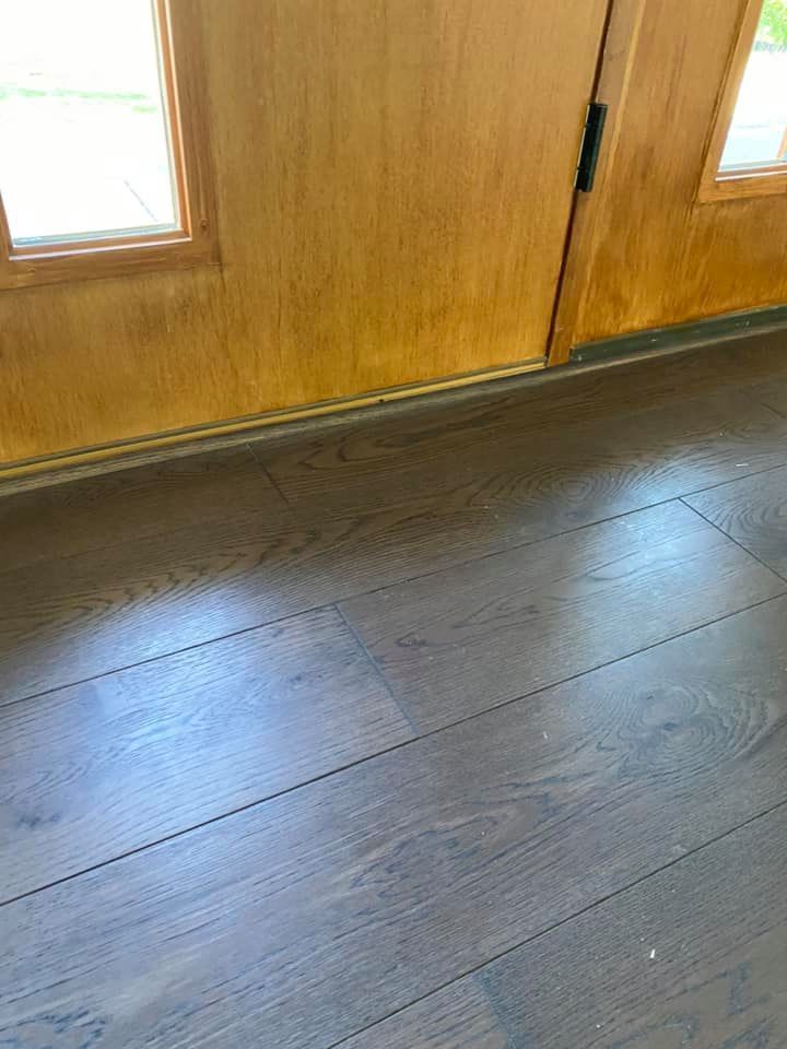 Wooden door with brown flooring. Sunlight reflecting on the floor.