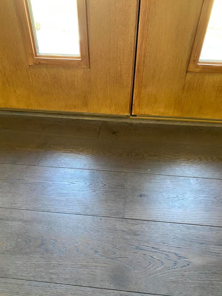Wooden door with glass panels above light wood floor.