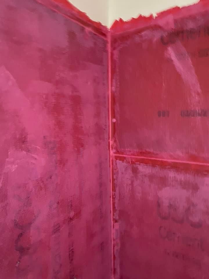 Pink waterproof membrane applied to the walls and corner of a shower.