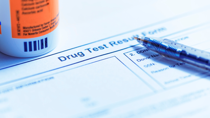 A bottle of pills is sitting on top of a drug test result form.