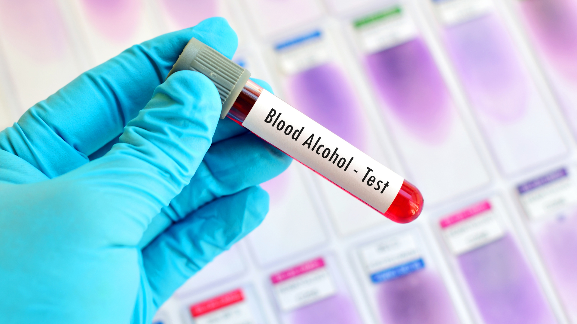 Gloved hand holding blood vial labeled