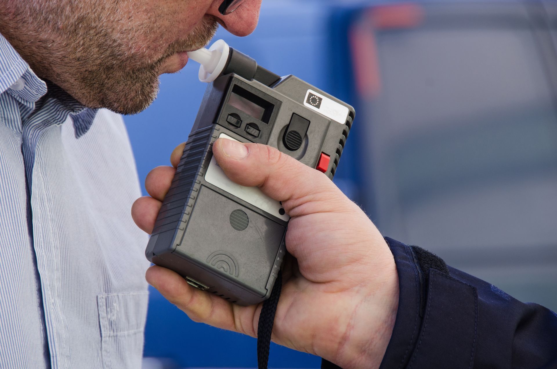 A man is being tested with a breathalyzer.