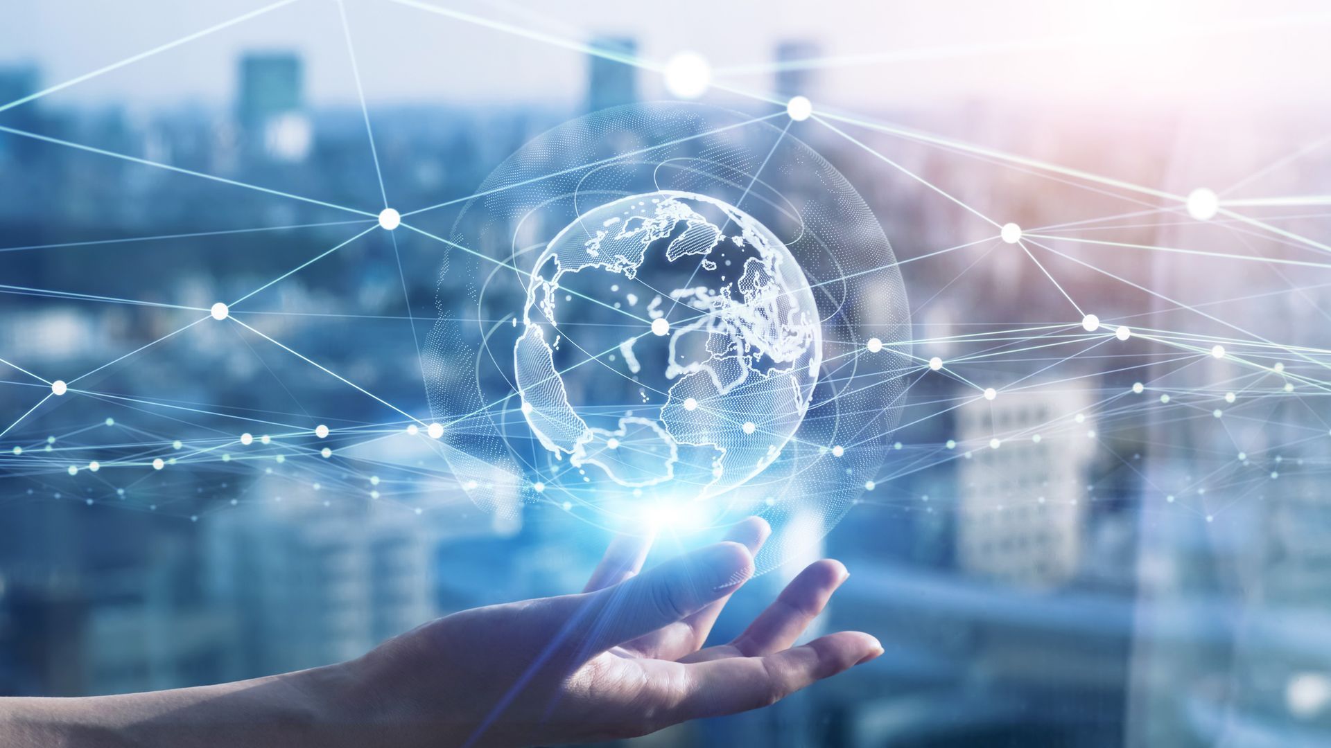 Hand holding a glowing globe overlaid with a network of interconnected lines, against a city backdrop.