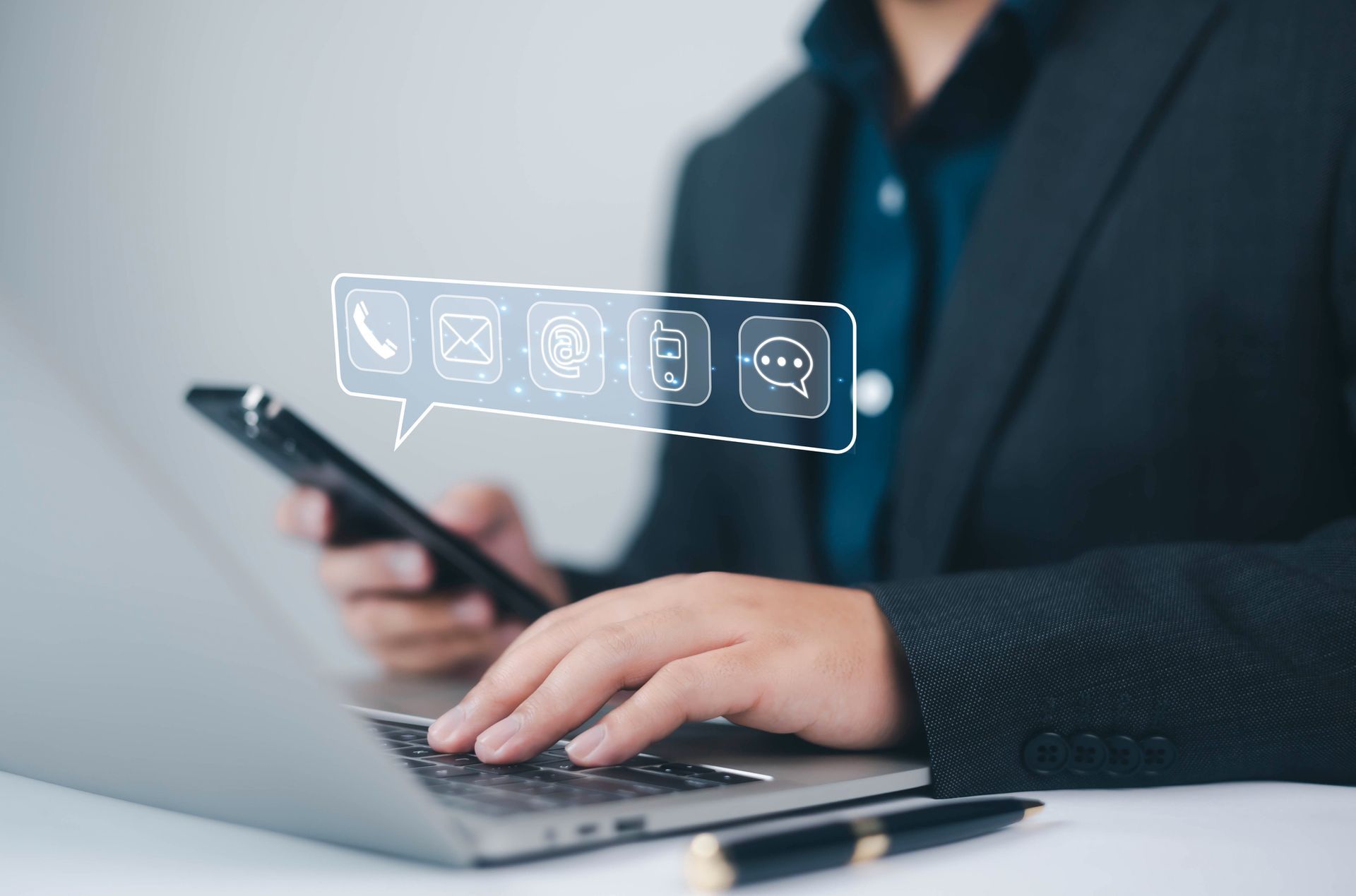 Person using laptop and smartphone with digital communication icons above.
