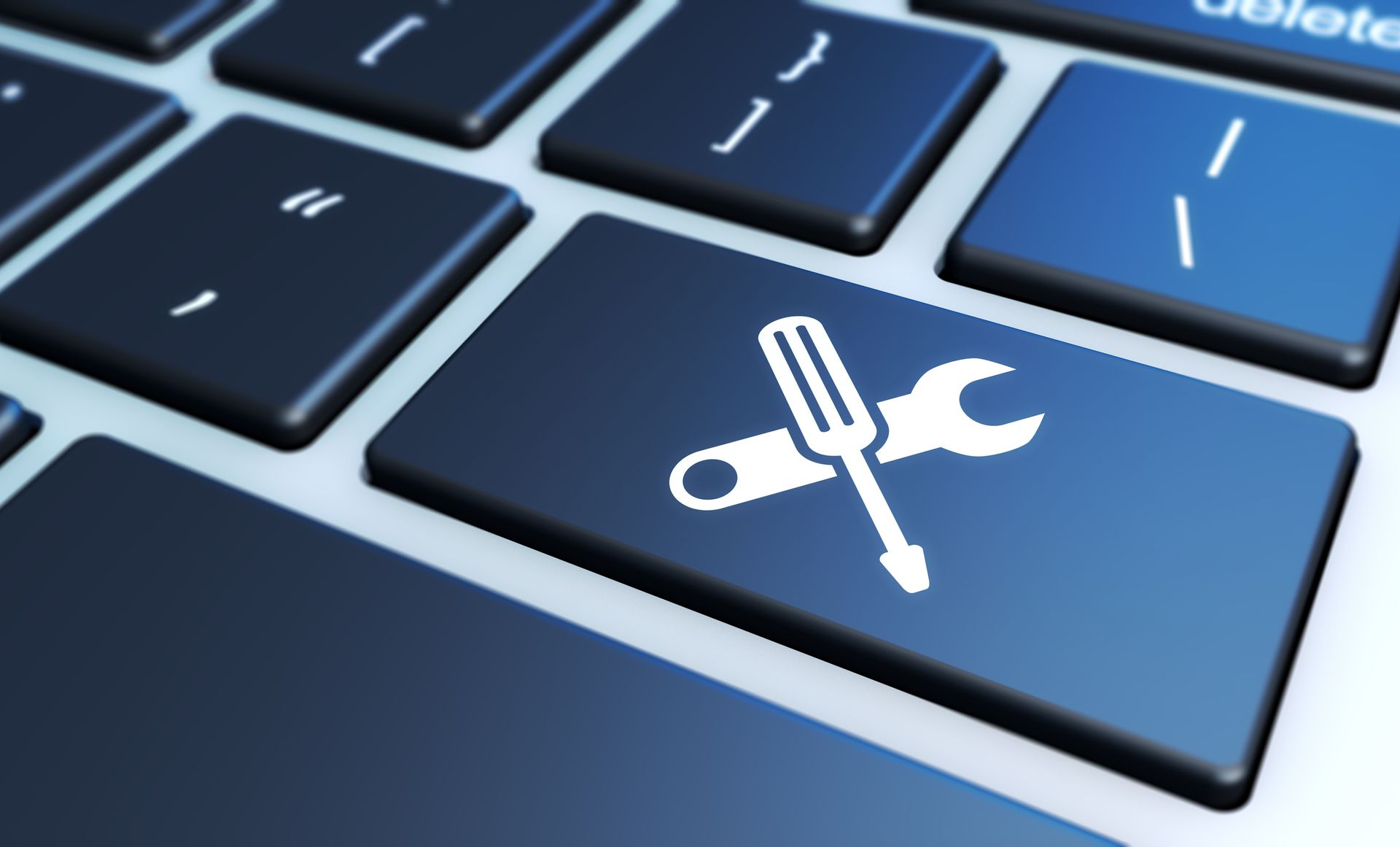 Close-up of a keyboard with a dark blue key displaying a white wrench and screwdriver icon, symbolizing settings or tools.