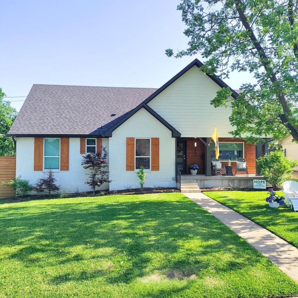White house with brown shutters, a walkway, and green lawn.