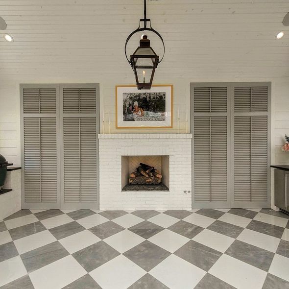 Gray shutters flank a fireplace with artwork, lantern, and checkered floor.