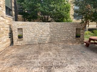 A patio with a brick wall and a picnic table.