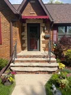 A brick house with a red awning over the front door