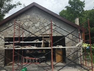 A garage is being remodeled with scaffolding around it getting a stone facade.