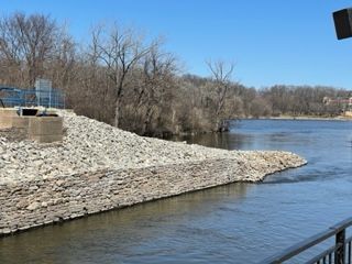 A river with a rocky shoreline and trees on the shore.