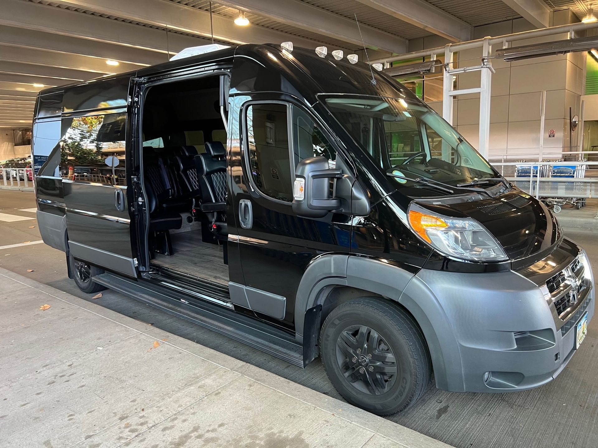Black passenger van with open side door, parked curbside.