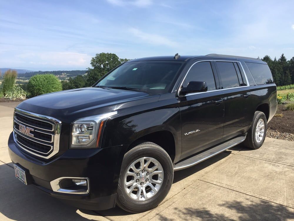 Black GMC Yukon SUV parked on a concrete surface in a sunny outdoor setting.