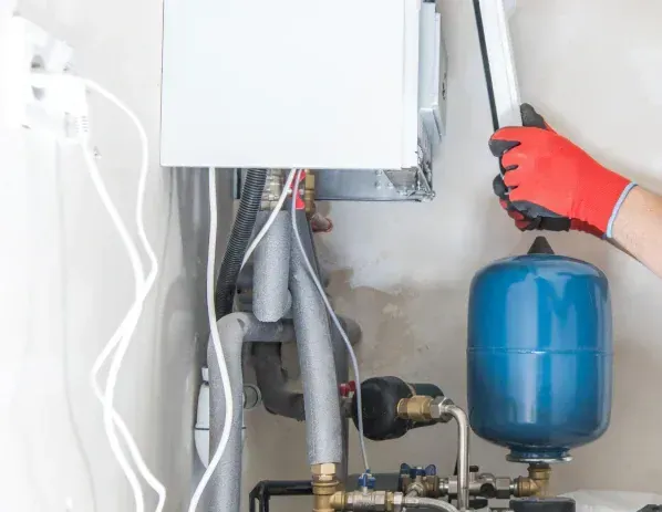 A person is working on a boiler in a room.