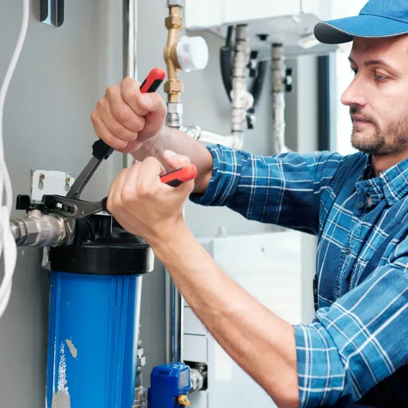 A man in a plaid shirt is working on a water filter