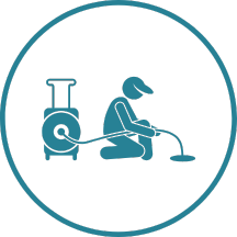 A man is kneeling down and using a vacuum cleaner to clean a pipe.