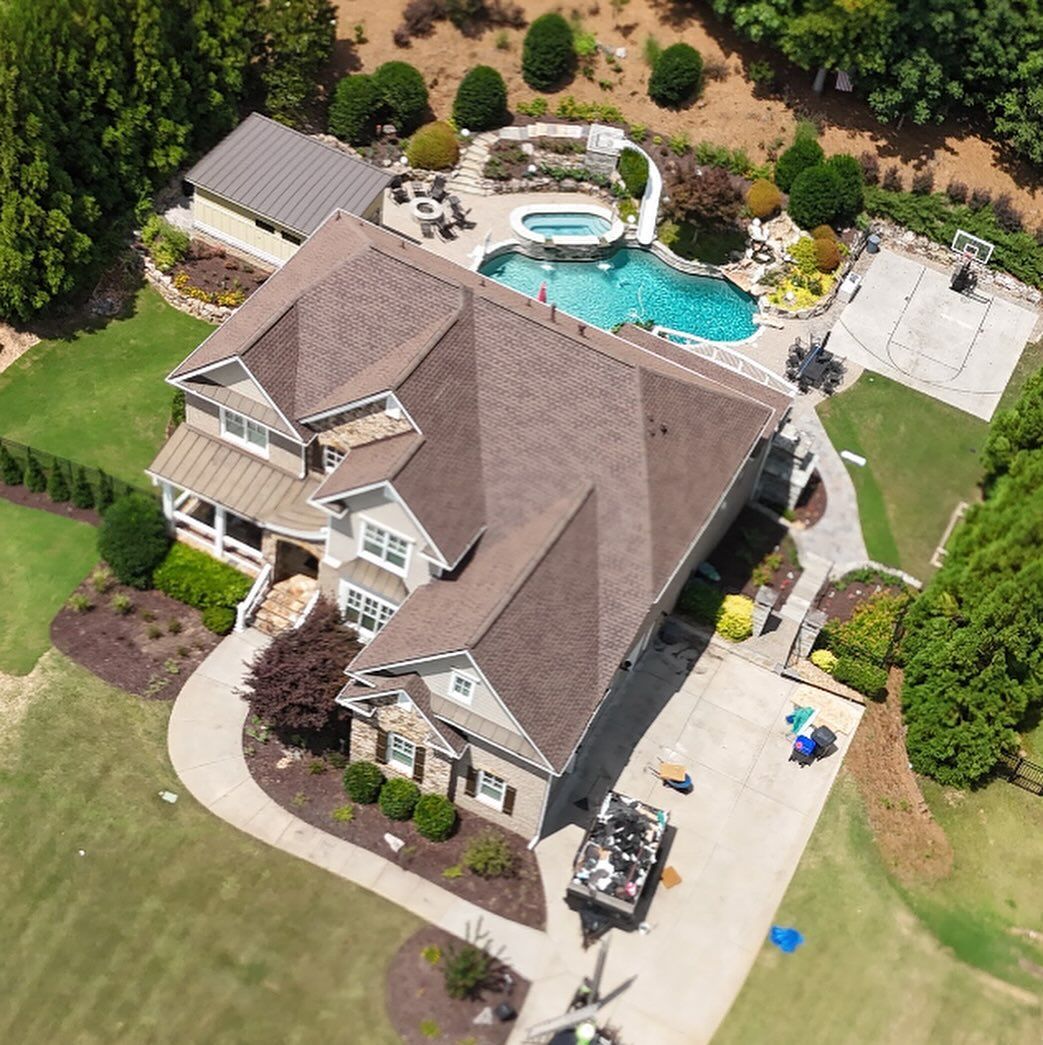 Aerial view of a large suburban house with a backyard swimming pool, patio, and basketball court.