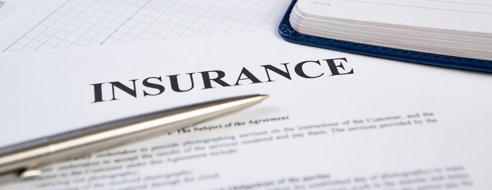 Close-up of insurance document with pen and notebook on desk. Close-up of insurance document with pen and notebook on desk.