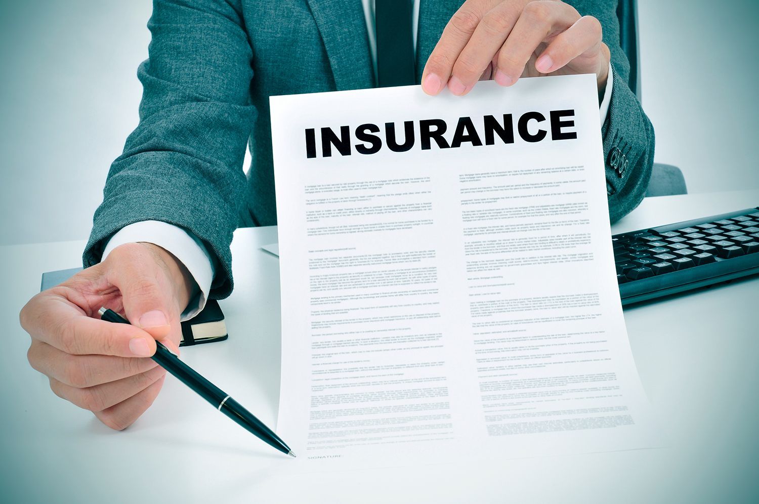 An unrecognized young man in a suit showing an insurance policy.