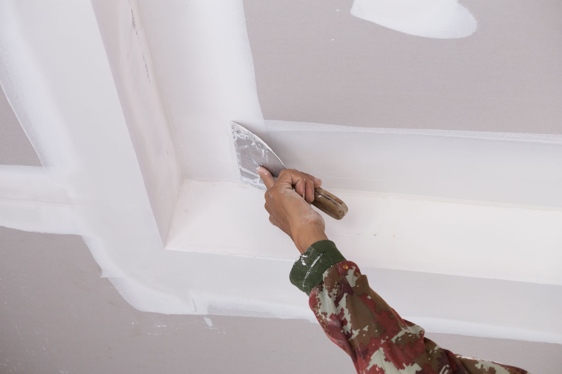 a person is plastering a ceiling with a spatula .