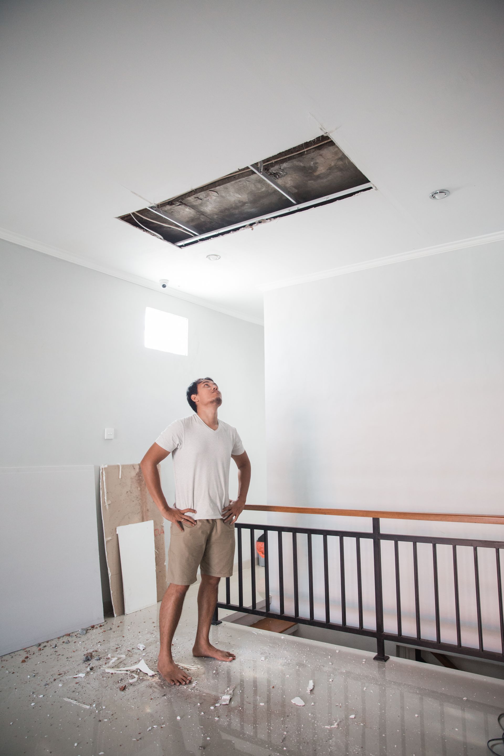 a man is standing in an empty room looking up at the ceiling .