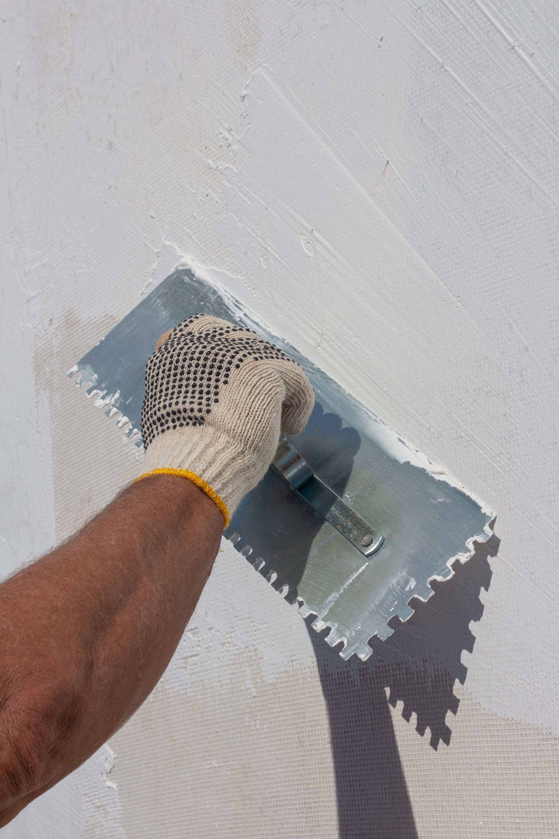 a person is using a trowel to plaster a wall .