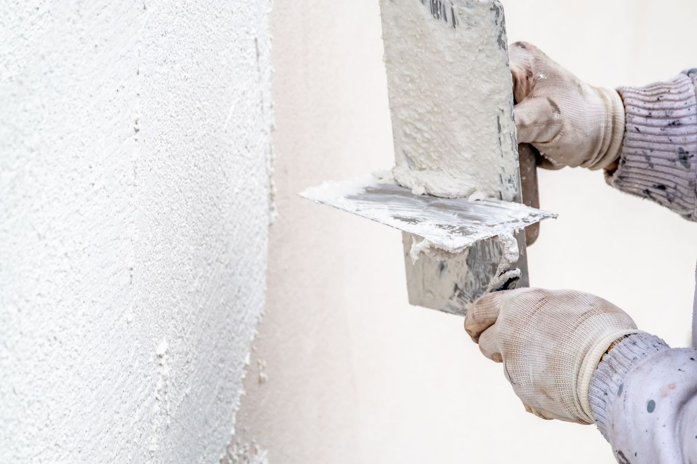 a person is plastering a wall with a trowel .
