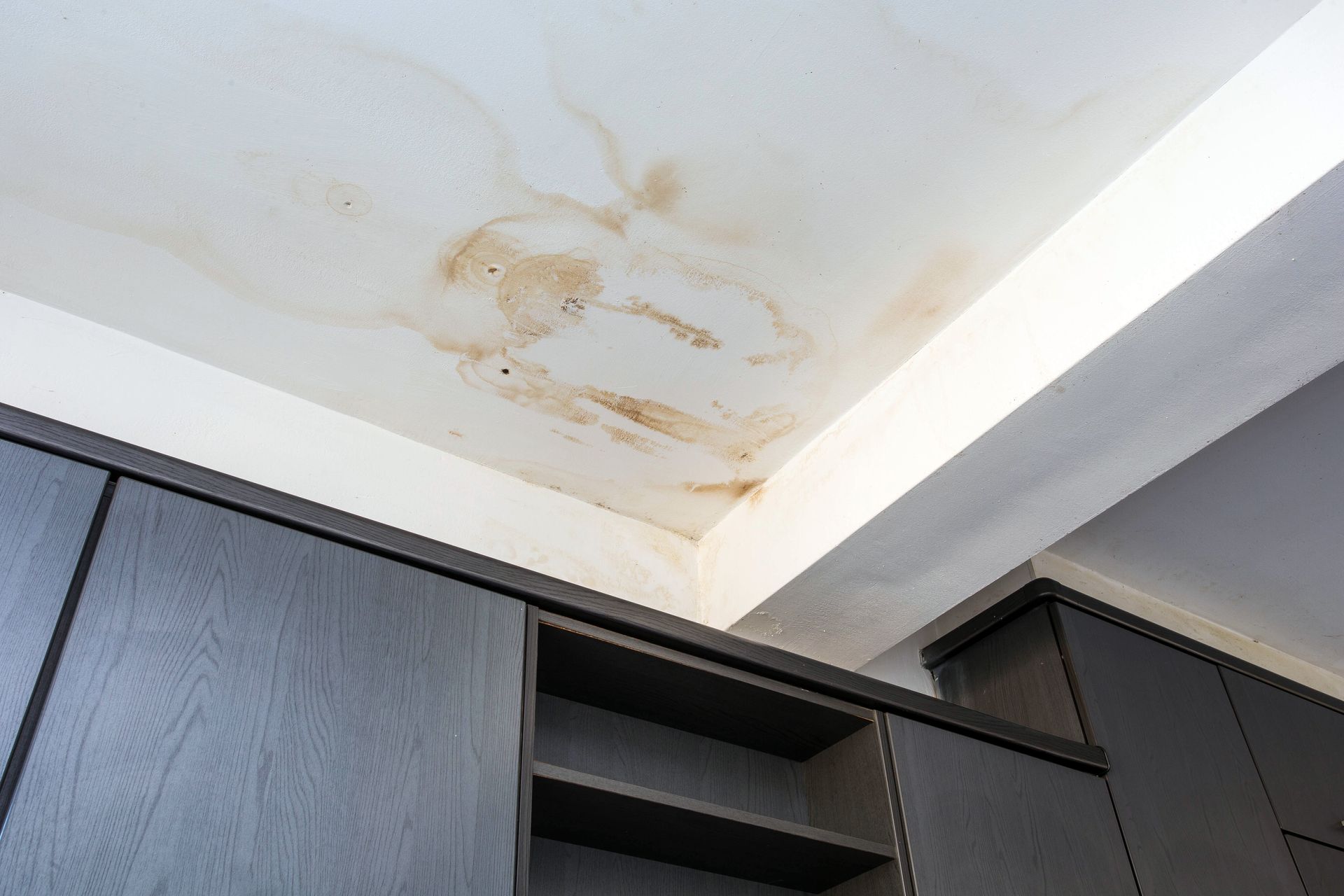 a ceiling with water stains on it in a room with cabinets .