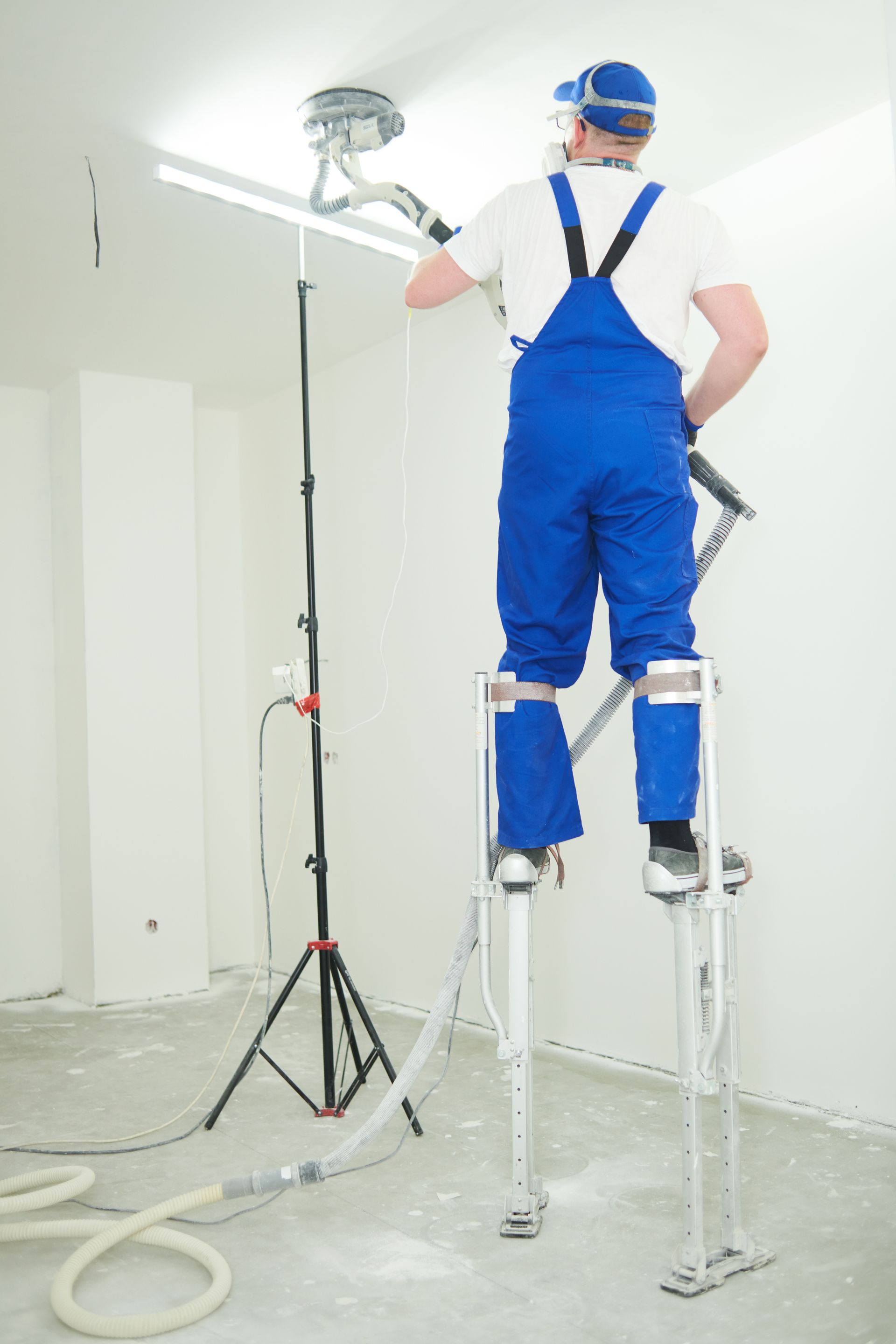 a man in blue overalls is standing on stilts in a room .