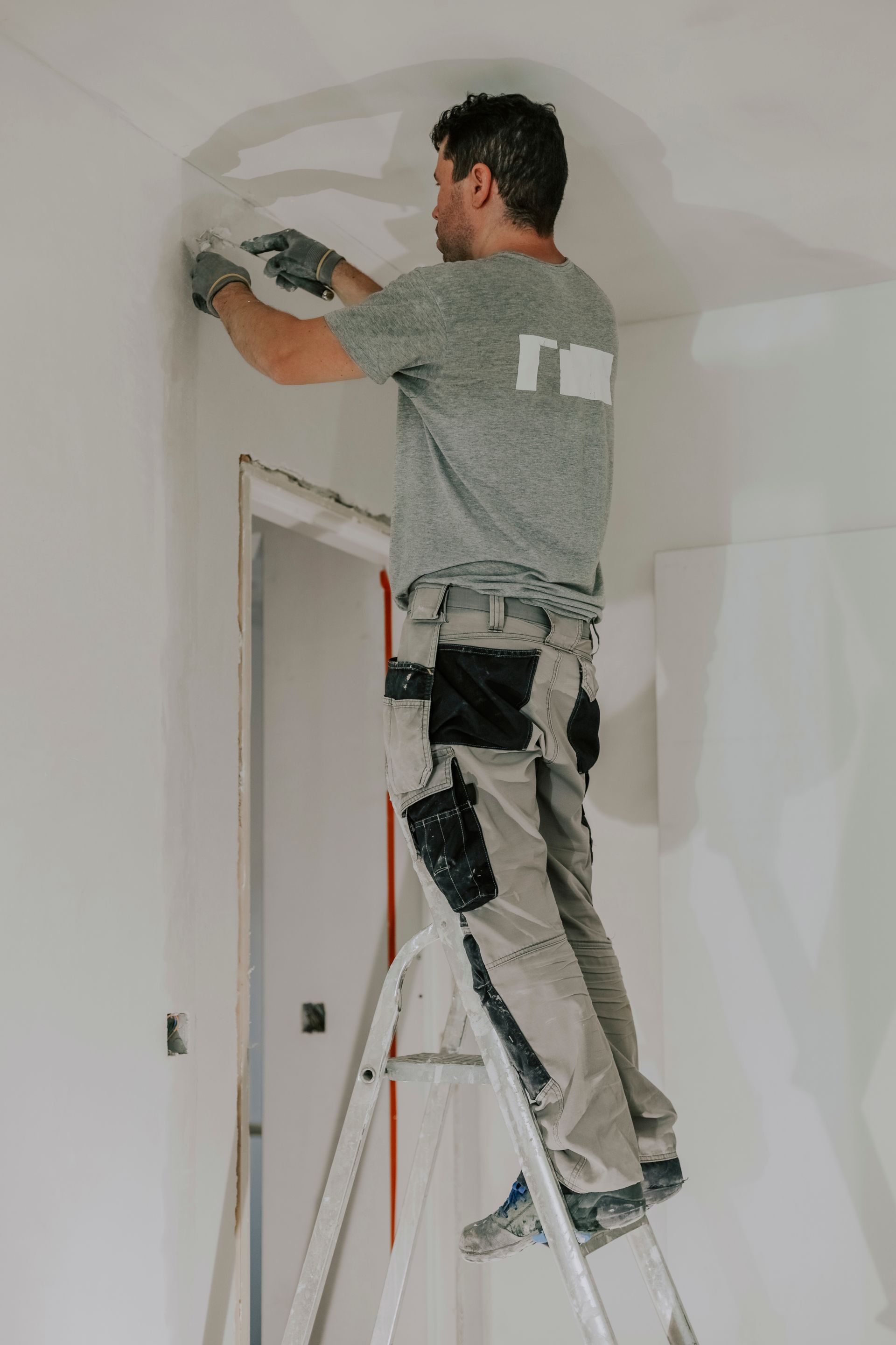 a man is standing on a ladder painting a wall .