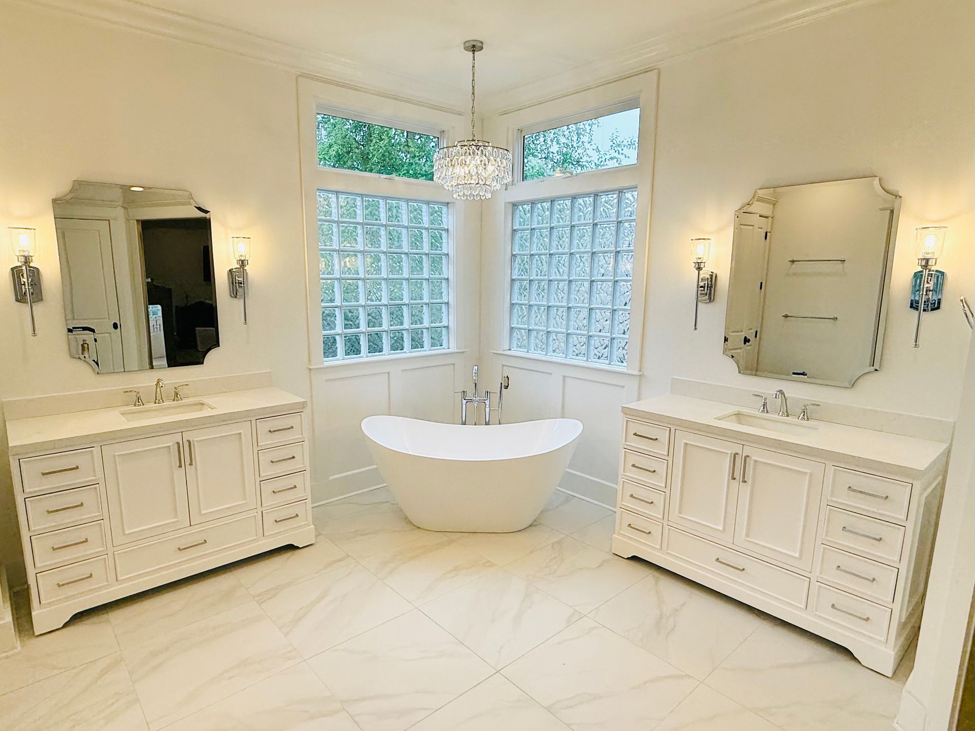 A bathroom with two sinks , a tub , and two mirrors.