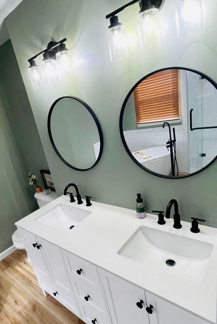 A bathroom with two sinks and two round mirrors.