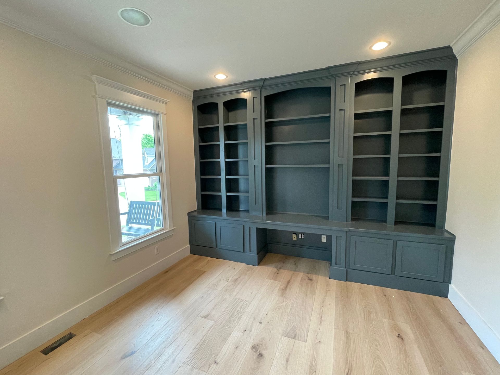 A room with a lot of shelves and a window.