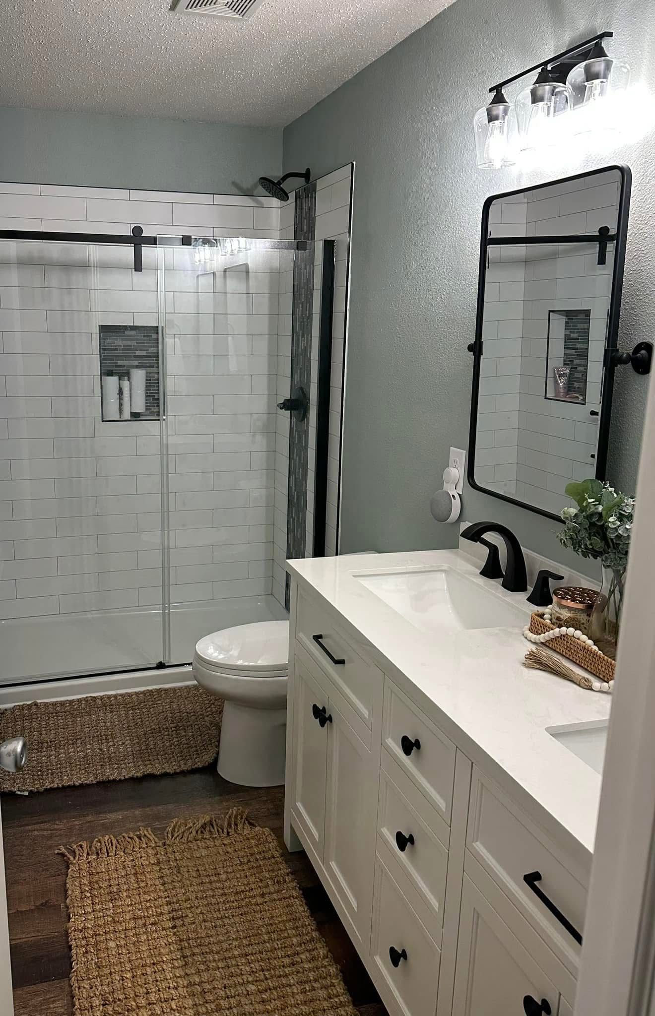 A bathroom with a toilet , sink , mirror and shower.