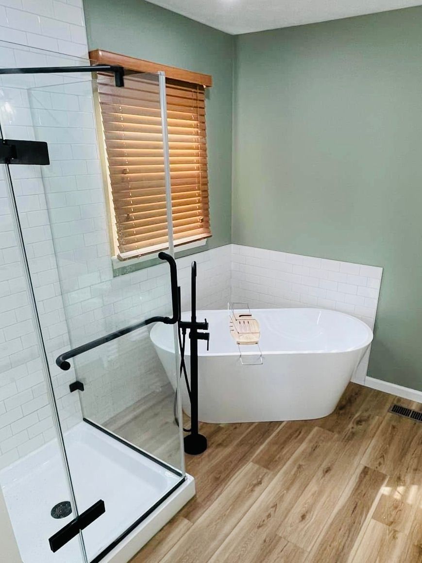 A bathroom with a tub , shower and window