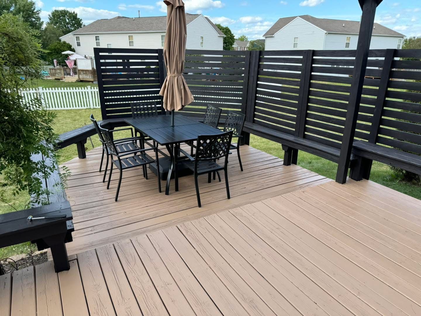 A wooden deck with a table and chairs and an umbrella.