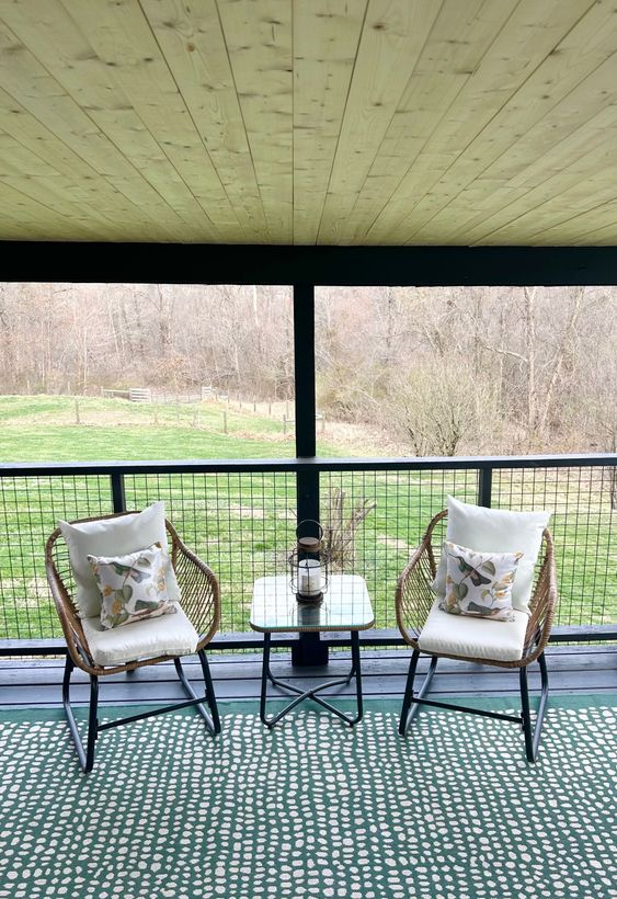 There are two chairs and a table on the porch.