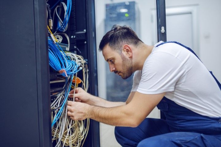 A man is working on a server in a data center.