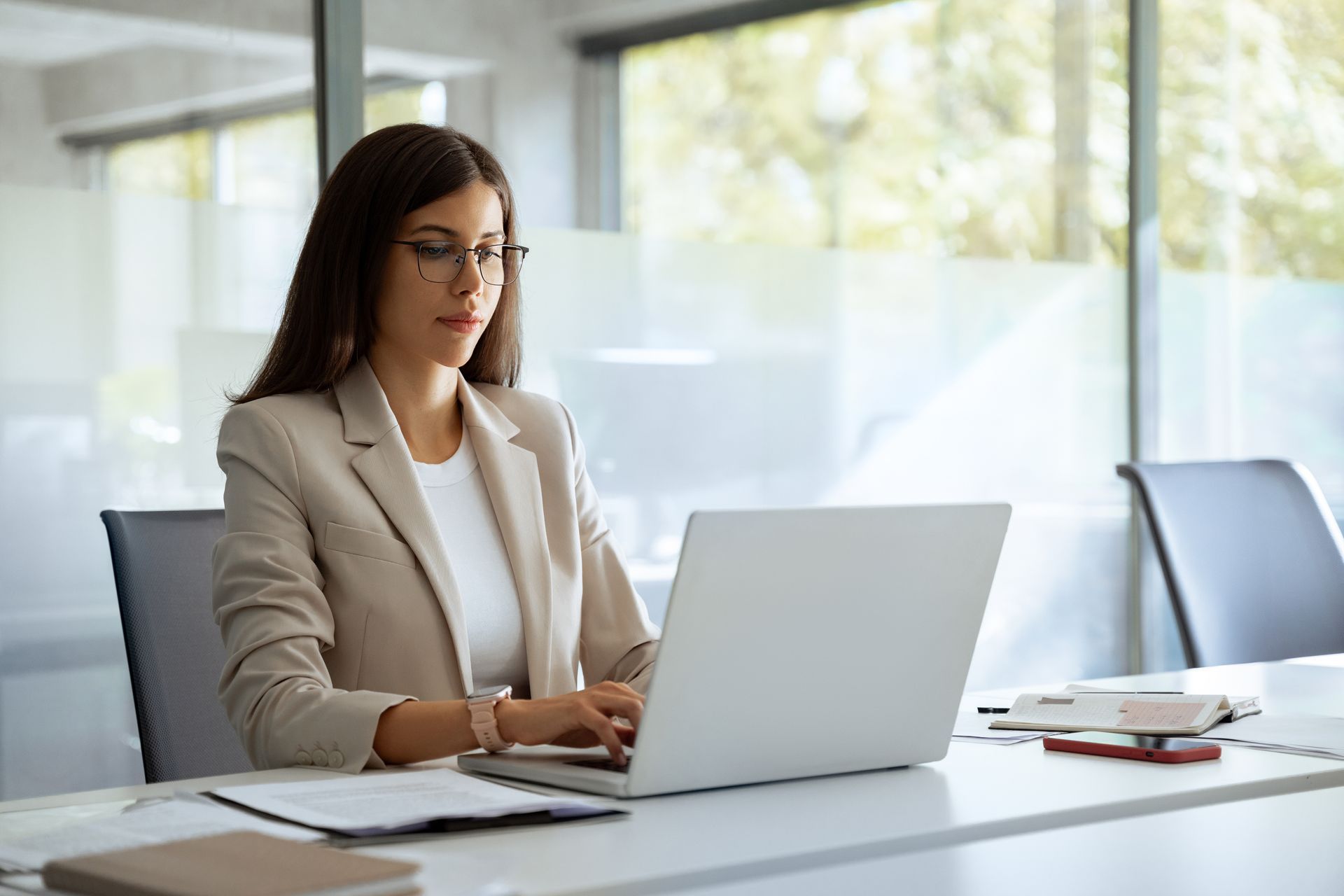 A woman is sitting at a desk using a laptop computer.