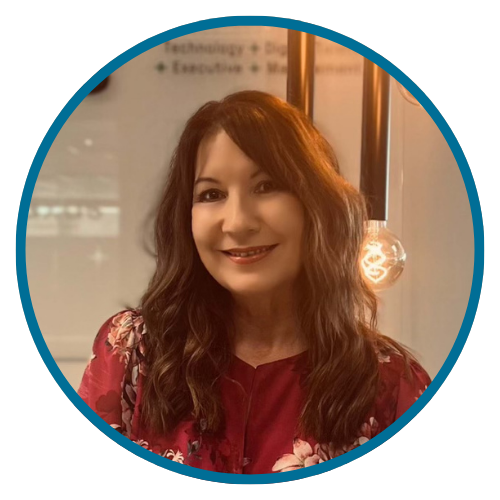 Woman with long brown hair, wearing a red floral blouse, smiling. Lit bulb and office setting in the background.