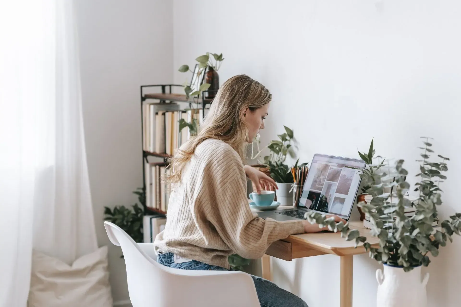 A woman is sitting at a desk using a laptop computer.
