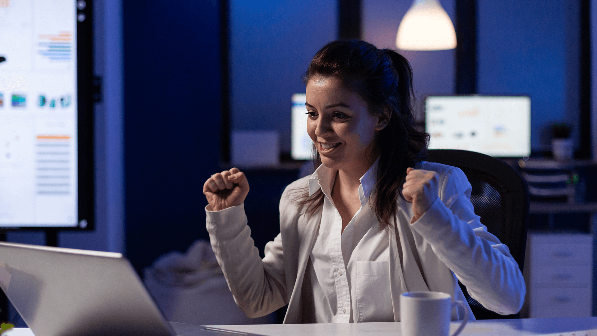 A woman is sitting at a desk in front of a laptop computer.